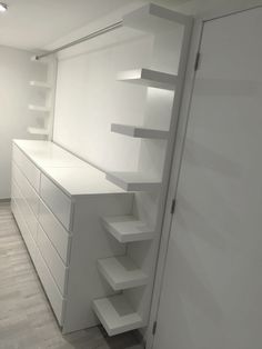 an empty room with white shelves and drawers