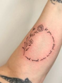 a woman's arm with a quote and flowers on it