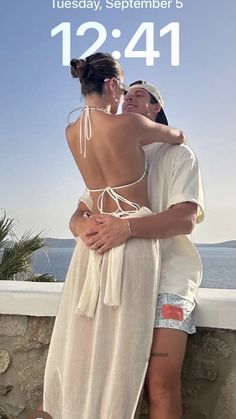 two women hugging each other in front of the ocean