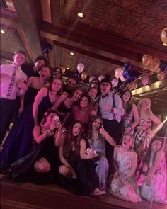 a group of people posing for a photo in front of balloons and confetti