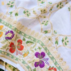 an embroidered cloth with flowers and leaves is laying on top of other fabric material that has been stitched together