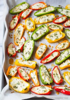 several peppers with cheese and herbs on them in a baking pan, ready to be cooked