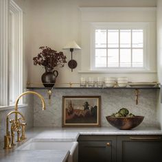 a kitchen with marble counter tops and gold faucets on the wall above it