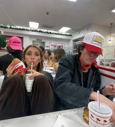 two people sitting at a table eating food and drinking soda in a fast food restaurant