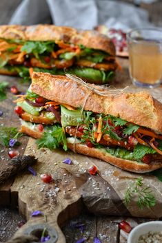 two sub sandwiches sitting on top of a wooden cutting board