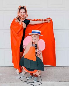 a woman standing next to a child dressed as a scarecrow and holding a microphone