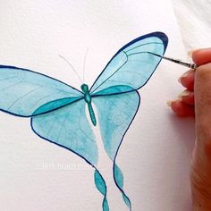 someone is drawing a blue butterfly on paper