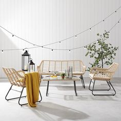 a table and chairs with yellow blankets on them in front of a string of lights