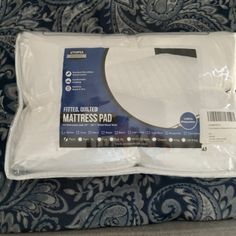 the folded mattress pad is sitting on top of a blue and white patterned bed sheet