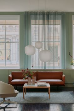 a living room with two couches and chairs in front of three large windows that have curtains on them