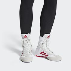 the legs and feet of a person wearing adidass white sneakers with red stripes