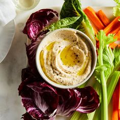 a plate with carrots, celery and lettuce next to dip