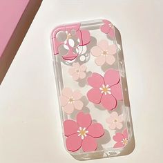 an iphone case with pink flowers on it sitting on a white table next to a pair of scissors