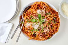 a bowl of spaghetti with sauce and parmesan cheese on the side next to a fork