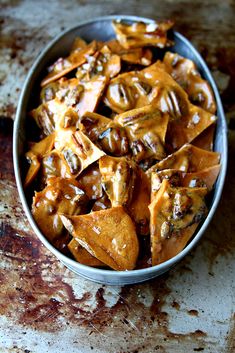 a bowl filled with sweet potato chips covered in caramel sauce on top of a rusted surface