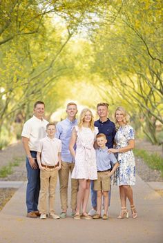 a family posing for a photo in front of trees with yellow leaves on the ground