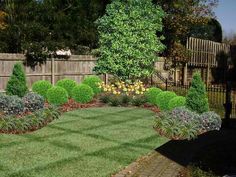 a garden with green grass and flowers in the middle, surrounded by wooden fenced area