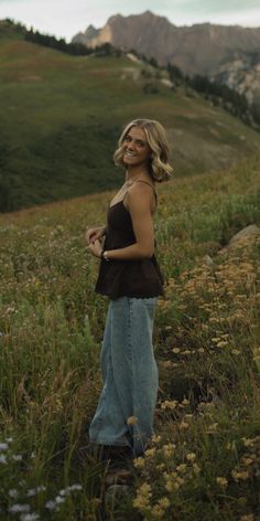 a woman standing on top of a lush green hillside