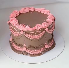 a chocolate cake with pink frosting on a white platter in front of a white background