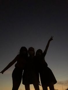 three girls standing in the dark with their arms up