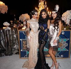 three beautiful women standing next to each other in front of a table with flowers and candles