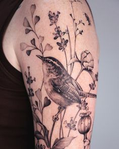 a woman's arm with a bird and flowers on it