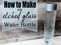 a glass bottle sitting on top of a wooden table next to a sign that says how to make an etched glass water bottle