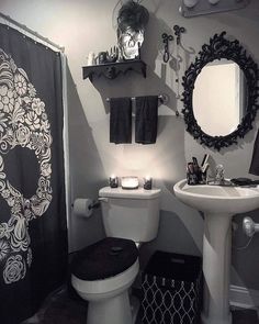 a black and white bathroom with skulls on the shower curtain, toilet seat cover and sink