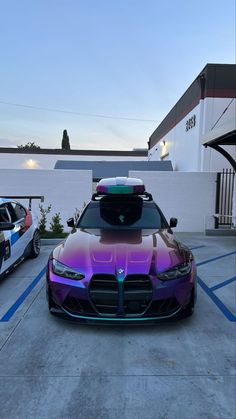 two cars that are parked next to each other in a parking lot, one is purple and the other is blue