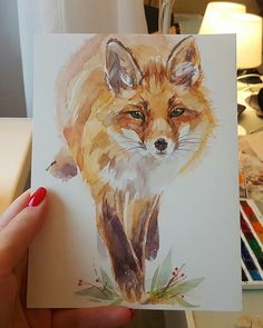 a person holding up a card with a painting of a fox on it