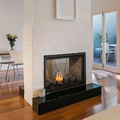 a fire place in the middle of a room with wood floors and white walls on either side