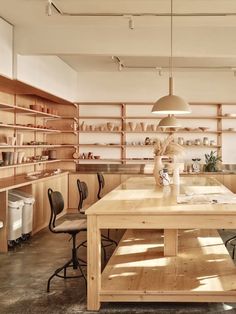 a wooden table surrounded by chairs and shelves