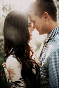 a man and woman standing next to each other in front of the sun with their faces close together