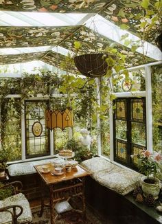 a room filled with lots of green plants and flowers on the ceiling above a table