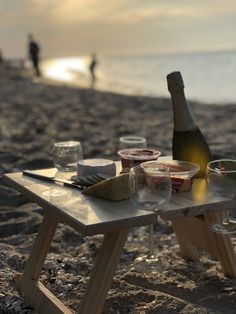 a picnic table with food and drinks on the beach