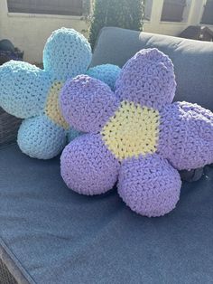 three crocheted flowers sitting on top of a blue couch next to each other