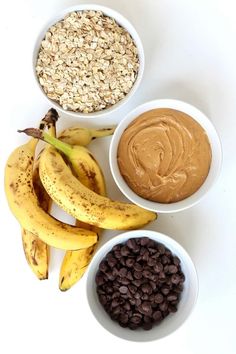 bananas, chocolate chips, and peanut butter are arranged in bowls on a white surface