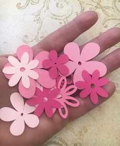 pink and white paper flowers are held in someone's hand