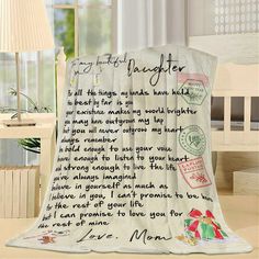 a white blanket with writing on it sitting in front of a window next to a lamp