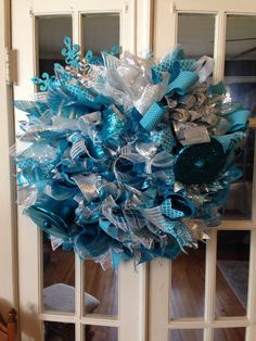 a blue and silver wreath hanging on the front door for someone to put in their home