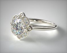 a white gold ring with an oval cut diamond surrounded by smaller round diamonds