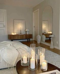 a living room filled with furniture and candles on top of a coffee table in front of a mirror