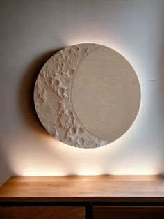 a large white circular object sitting on top of a wooden table next to a wall