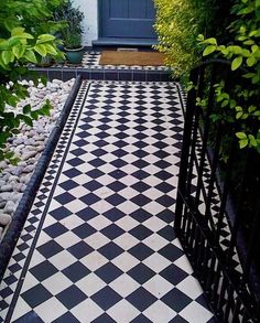 a black and white checkered tile floor in front of a door with green plants