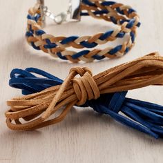 two braided leather bracelets on a wooden surface