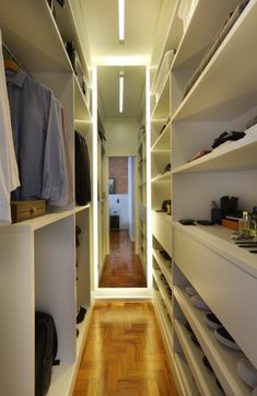 an empty walk - in closet with white shelves and wooden floors