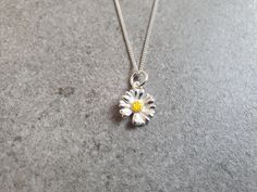 a silver necklace with a yellow flower on the front and center piece in the middle