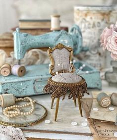 an old chair sitting on top of a table next to some thread and sewing needles