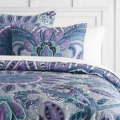 a bed with purple and blue bedspread, pillows and pillow cases on it