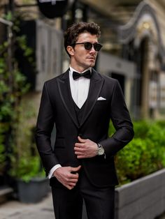 a man in a tuxedo is standing on the street